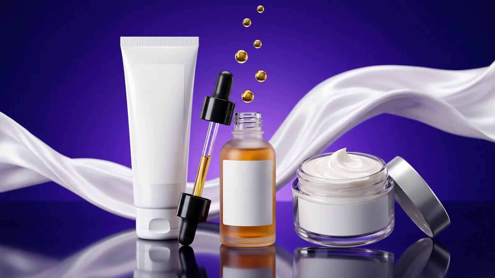 An unbranded sunscreen tube, a glass dropper bottle of amber serum and an open jar of glossy cream with a ribbon of white silk, on a deep violet to ultramarine backdrop